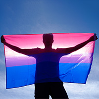 silhouette of man holding a colorful flag