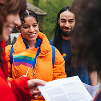 group of young adults gathered togther and holding lgbtq flags