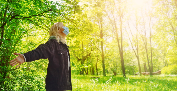 Woman wearing face mask, standing in the woods