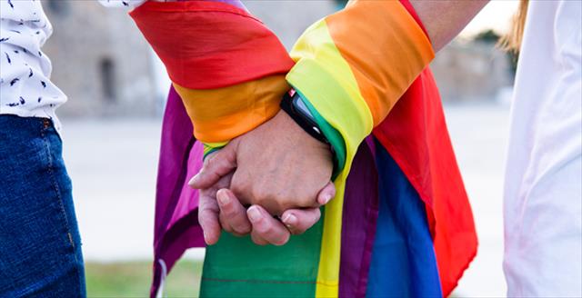 Close-up of holding hands with LGBTQIA+ flag 