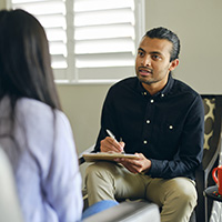 man holding a clipboard while talking with a young woman