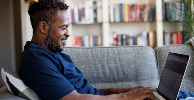 A man looking at his computer sitting on his couch.