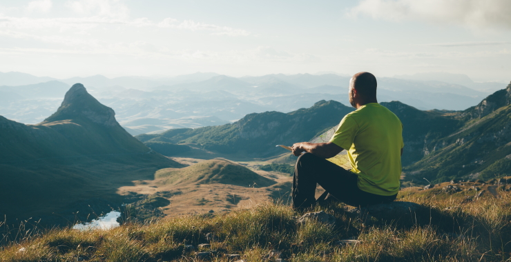 man sitting on top of a mountain looking out