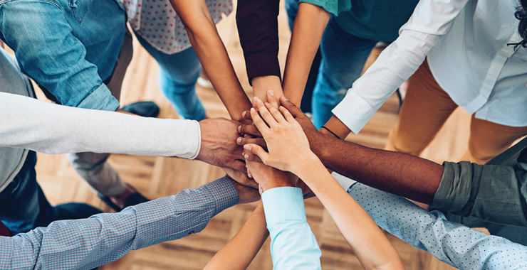 A group of people bringing their hands together to show unity, solidarity, and collaboration